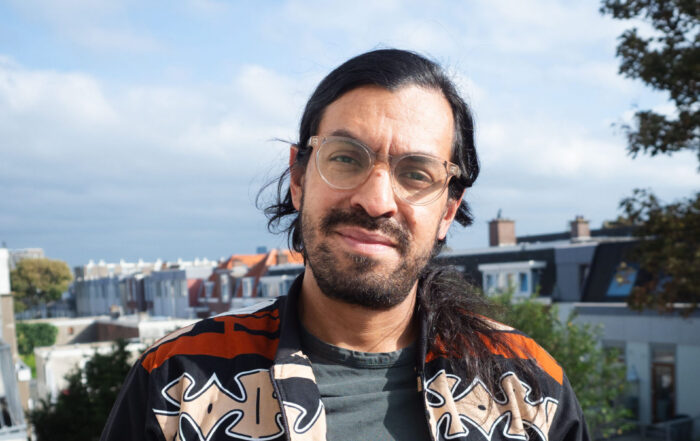 Julian kijkt de camera in. Op de achtergrond een blauwe lucht.